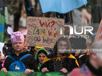 People wear animal masks and hold signs and banners as they participate in the street parade for the Climate Pride on November 16, 2024 in R...