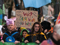 People wear animal masks and hold signs and banners as they participate in the street parade for the Climate Pride on November 16, 2024 in R...