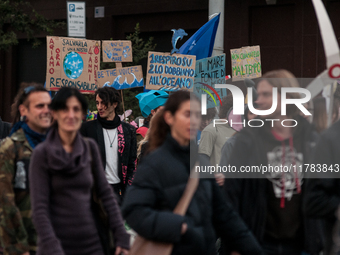 People wear animal masks and hold signs and banners as they participate in the street parade for the Climate Pride on November 16, 2024 in R...