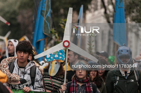 People wear animal masks and hold signs and banners as they participate in the street parade for the Climate Pride on November 16, 2024 in R...