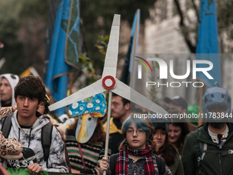 People wear animal masks and hold signs and banners as they participate in the street parade for the Climate Pride on November 16, 2024 in R...