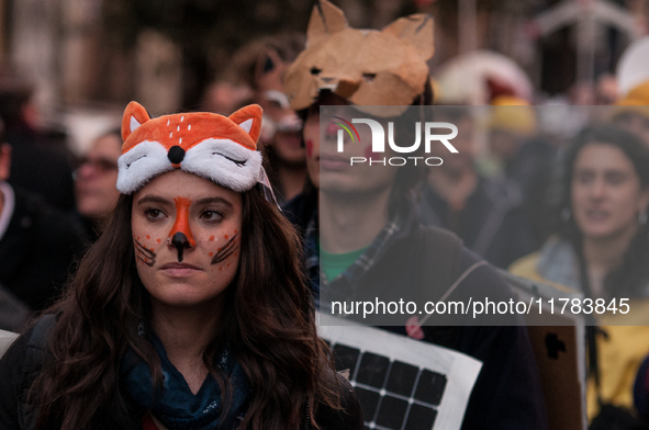 People wear animal masks and hold signs and banners as they participate in the street parade for the Climate Pride on November 16, 2024 in R...