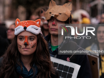 People wear animal masks and hold signs and banners as they participate in the street parade for the Climate Pride on November 16, 2024 in R...