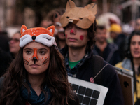 People wear animal masks and hold signs and banners as they participate in the street parade for the Climate Pride on November 16, 2024 in R...