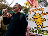 People wear animal masks and hold signs and banners as they participate in the street parade for the Climate Pride on November 16, 2024 in R...