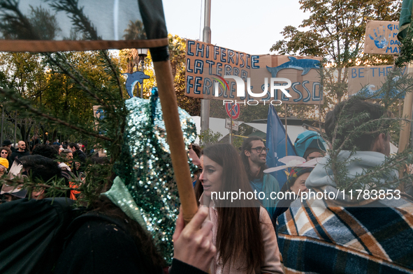 People wear animal masks and hold signs and banners as they participate in the street parade for the Climate Pride on November 16, 2024 in R...