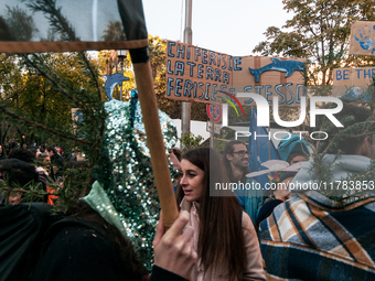 People wear animal masks and hold signs and banners as they participate in the street parade for the Climate Pride on November 16, 2024 in R...