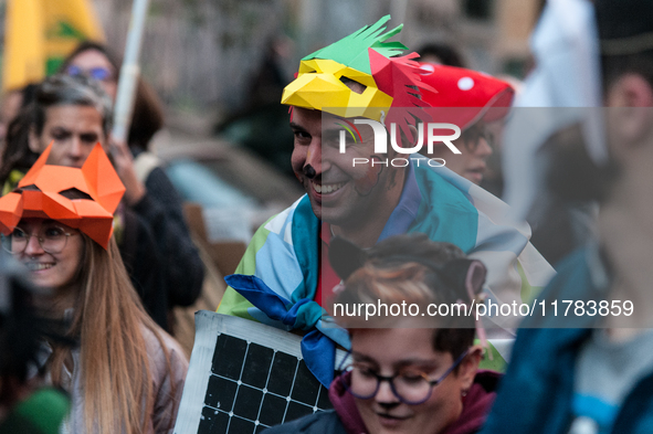 People wear animal masks and hold signs and banners as they participate in the street parade for the Climate Pride on November 16, 2024 in R...