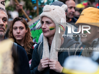 People wear animal masks and hold signs and banners as they participate in the street parade for the Climate Pride on November 16, 2024 in R...