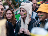 People wear animal masks and hold signs and banners as they participate in the street parade for the Climate Pride on November 16, 2024 in R...