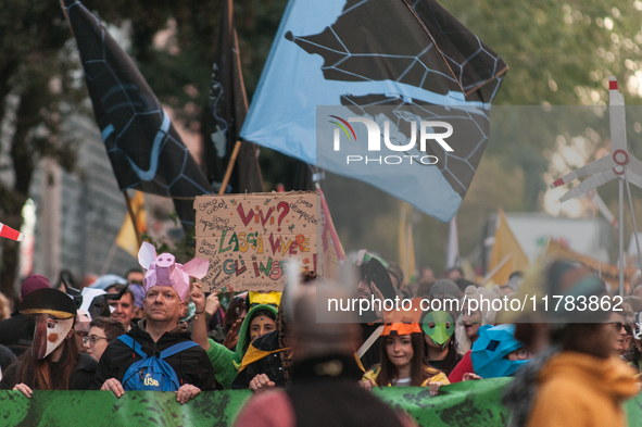 People wear animal masks and hold signs and banners as they participate in the street parade for the Climate Pride on November 16, 2024 in R...