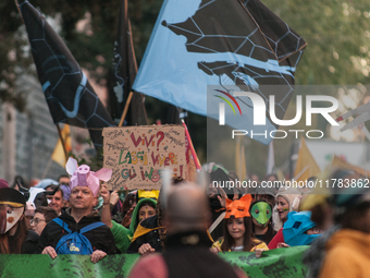 People wear animal masks and hold signs and banners as they participate in the street parade for the Climate Pride on November 16, 2024 in R...