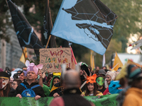 People wear animal masks and hold signs and banners as they participate in the street parade for the Climate Pride on November 16, 2024 in R...