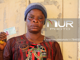 Mary Demehin shows her voter's card after voting during the 2024 Governorship election for Ondo State in Obenla, Ilaje, Local Government Are...