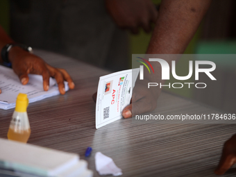 An agent of the All Progressives Congress (APC) places his identification card on a table during the 2024 Governorship election for Ondo Sta...