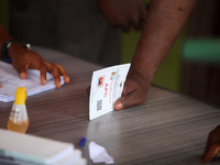 An agent of the All Progressives Congress (APC) places his identification card on a table during the 2024 Governorship election for Ondo Sta...