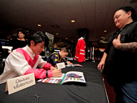 Jockeys Daisuke Fukumoto, left, and Fraser Aebly sign autographs to help raise funds for LongRun Thoroughbred Retirement Society, an organiz...