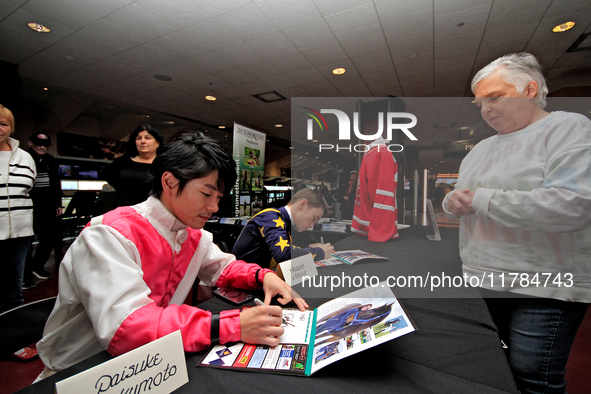 Jockeys Daisuke Fukumoto, left, and Fraser Aebly sign autographs to help raise funds for LongRun Thoroughbred Retirement Society, an organiz...