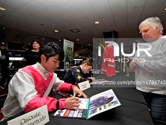 Jockeys Daisuke Fukumoto, left, and Fraser Aebly sign autographs to help raise funds for LongRun Thoroughbred Retirement Society, an organiz...