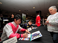 Jockeys Daisuke Fukumoto, left, and Fraser Aebly sign autographs to help raise funds for LongRun Thoroughbred Retirement Society, an organiz...