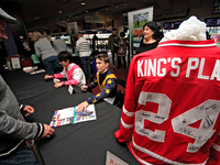 Jockeys Daisuke Fukumoto, left, and Fraser Aebly sign autographs to help raise funds for LongRun Thoroughbred Retirement Society, an organiz...