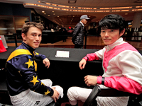 Jockeys Fraser Aebly, left, and Daisuke Fukumoto sign autographs to help raise funds for LongRun Thoroughbred Retirement Society, an organiz...