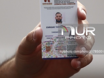 A person shows his new permanent driver's license after applying for it at the processing point installed in the Ciudad Deportiva, in the Iz...