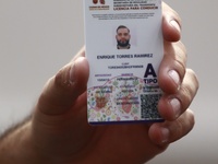 A person shows his new permanent driver's license after applying for it at the processing point installed in the Ciudad Deportiva, in the Iz...