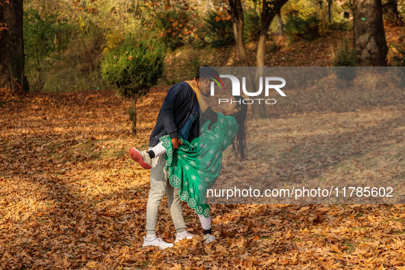 Indian tourists dance on fallen Chinar tree leaves inside a Mughal garden in Srinagar, Jammu and Kashmir, on November 17, 2024. Autumn, loca...