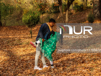 Indian tourists dance on fallen Chinar tree leaves inside a Mughal garden in Srinagar, Jammu and Kashmir, on November 17, 2024. Autumn, loca...