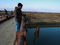 A boy retrieves a polythene bag after casting his fishing rod to catch fish in Wular Lake in Sopore, Jammu and Kashmir, India, on November 1...