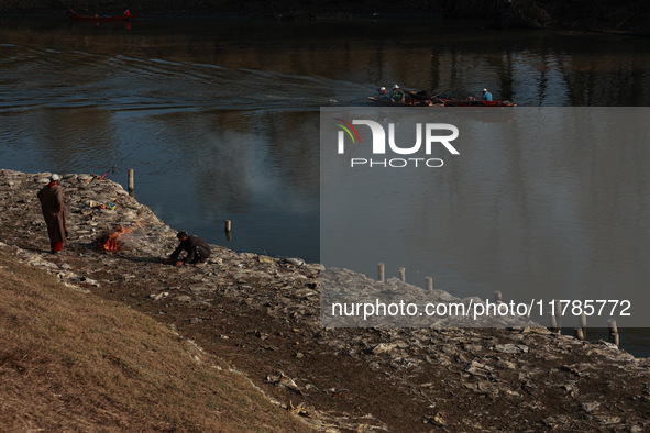 Young boys burn trash to stay warm as they brave the chilly weather to catch fish on the banks of Wular Lake in Sopore, Jammu and Kashmir, I...