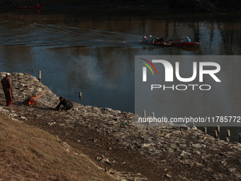 Young boys burn trash to stay warm as they brave the chilly weather to catch fish on the banks of Wular Lake in Sopore, Jammu and Kashmir, I...