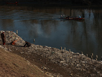 Young boys burn trash to stay warm as they brave the chilly weather to catch fish on the banks of Wular Lake in Sopore, Jammu and Kashmir, I...