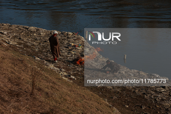 Young boys burn trash to stay warm as they brave the chilly weather to catch fish on the banks of Wular Lake in Sopore, Jammu and Kashmir, I...