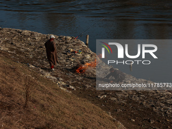 Young boys burn trash to stay warm as they brave the chilly weather to catch fish on the banks of Wular Lake in Sopore, Jammu and Kashmir, I...