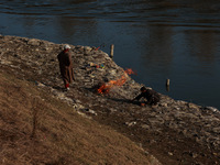 Young boys burn trash to stay warm as they brave the chilly weather to catch fish on the banks of Wular Lake in Sopore, Jammu and Kashmir, I...