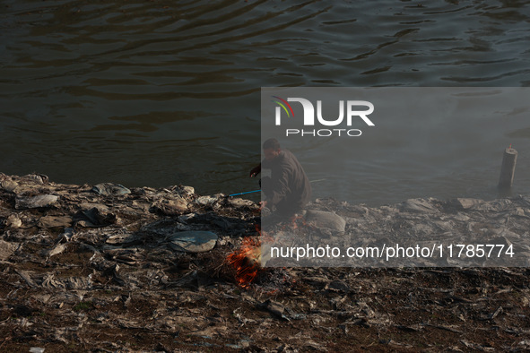 Young boys burn trash to stay warm as they brave the chilly weather to catch fish on the banks of Wular Lake in Sopore, Jammu and Kashmir, I...