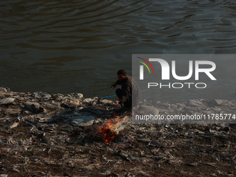 Young boys burn trash to stay warm as they brave the chilly weather to catch fish on the banks of Wular Lake in Sopore, Jammu and Kashmir, I...