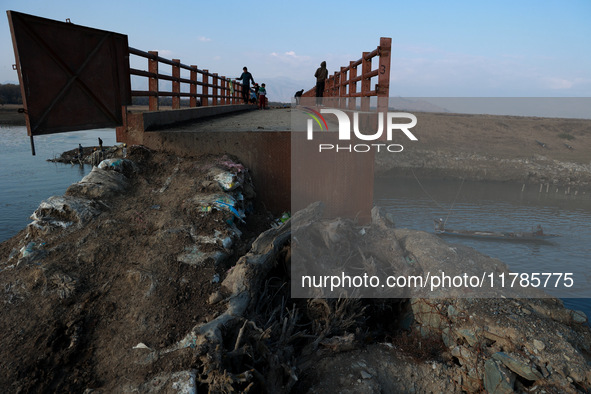 Kashmiri boys catch fish while sitting on a bridge with a dangerous entrance in Sopore, Jammu and Kashmir, India, on November 17, 2024. 