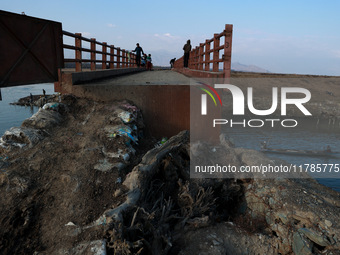 Kashmiri boys catch fish while sitting on a bridge with a dangerous entrance in Sopore, Jammu and Kashmir, India, on November 17, 2024. (