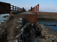 Kashmiri boys catch fish while sitting on a bridge with a dangerous entrance in Sopore, Jammu and Kashmir, India, on November 17, 2024. (