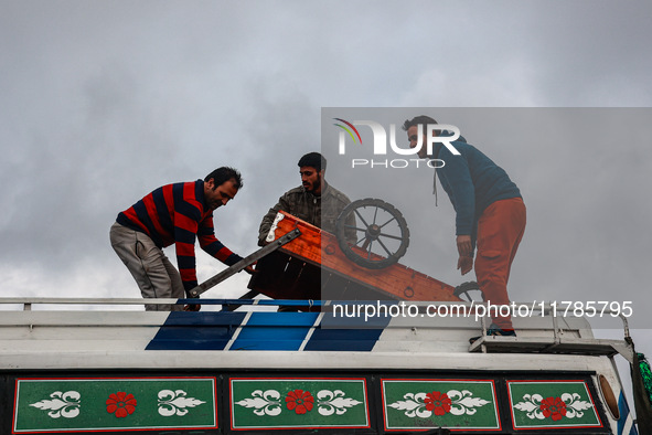 Kashmiri men place a handcart on top of a bus to transport it to a different location in Sopore, Jammu and Kashmir, India, on November 16, 2...