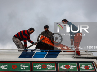 Kashmiri men place a handcart on top of a bus to transport it to a different location in Sopore, Jammu and Kashmir, India, on November 16, 2...