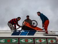 Kashmiri men place a handcart on top of a bus to transport it to a different location in Sopore, Jammu and Kashmir, India, on November 16, 2...