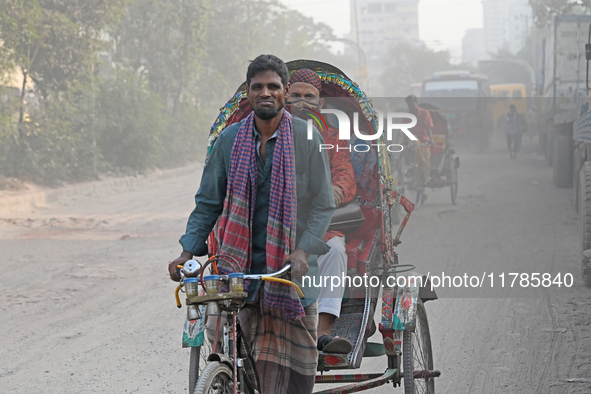 People navigate a dusty road in Dhaka, Bangladesh, on November 17, 2024. The city has ranked first on the list of cities with the worst air...