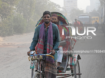 People navigate a dusty road in Dhaka, Bangladesh, on November 17, 2024. The city has ranked first on the list of cities with the worst air...