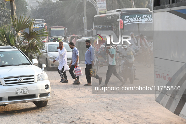 People navigate a dusty road in Dhaka, Bangladesh, on November 17, 2024. The city has ranked first on the list of cities with the worst air...