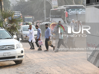 People navigate a dusty road in Dhaka, Bangladesh, on November 17, 2024. The city has ranked first on the list of cities with the worst air...