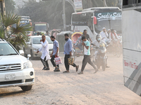 People navigate a dusty road in Dhaka, Bangladesh, on November 17, 2024. The city has ranked first on the list of cities with the worst air...